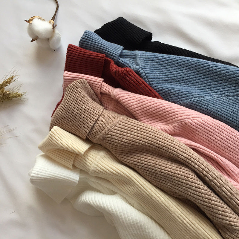 A collection of ribbed knit turtleneck sweaters in soft pastel and neutral tones, including beige, pink, red, blue, black, and cream