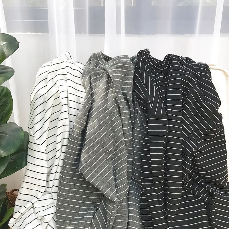 Three long-sleeved striped cotton tees in white, gray, and black with thin horizontal stripes