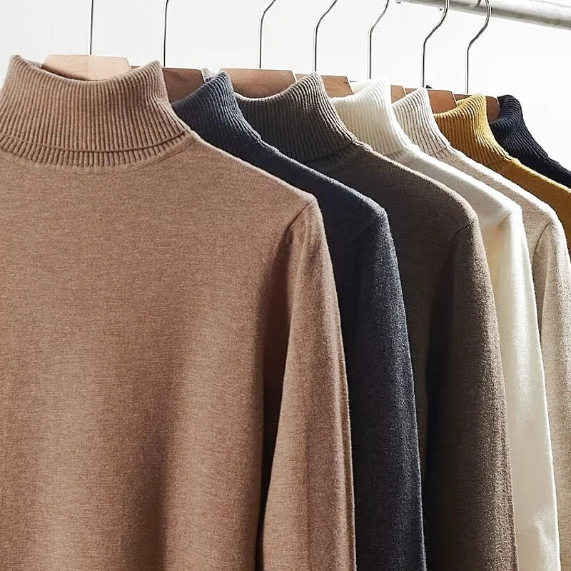 A row of soft, ribbed turtleneck sweaters in earthy tones like camel, navy, and cream hang neatly on wooden hangers