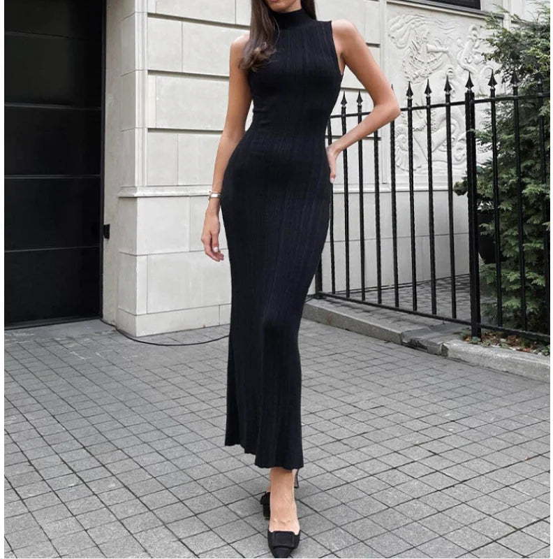 A sleek, black ribbed knit high-neck midi dress with a form-fitting silhouette and flared hem