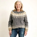 A cozy, chunky-knit sweater in shades of gray and cream with a traditional nordic-inspired pattern