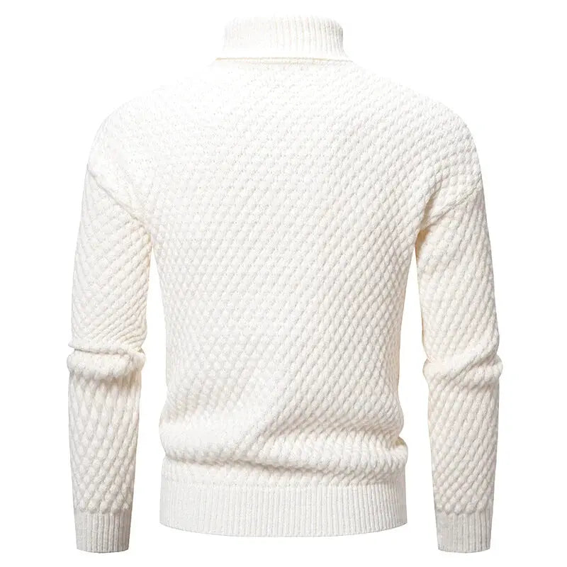 A cream-colored, textured knit turtleneck sweater with a diamond-patterned weave and ribbed cuffs