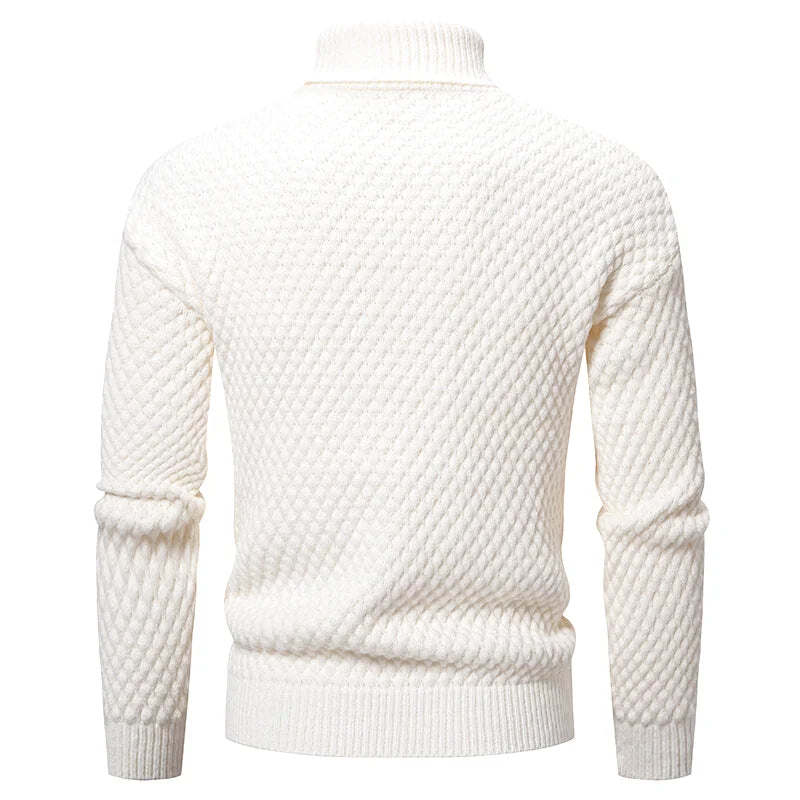 A cream-colored, textured knit turtleneck sweater with a diamond-patterned weave and ribbed cuffs