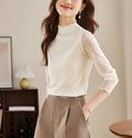 White sheer long-sleeved blouse with a high neckline and ruffled trim