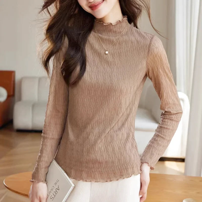 A beige, sheer long-sleeved top with a ruffled high neckline and subtle wavy texture