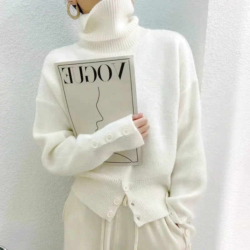 A soft, off-white turtleneck sweater with a ribbed texture and decorative buttons along the cuffs and front