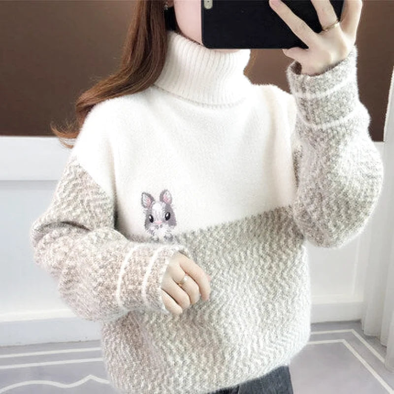 A cozy off-white and beige turtleneck sweater with a textured knit, featuring a cute embroidered hamster on the chest
