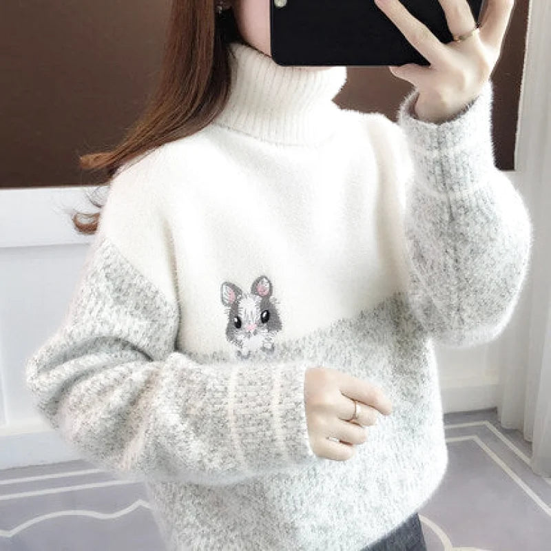 A cozy, two-tone turtleneck sweater in soft white and gray with a charming embroidered hamster design on the chest