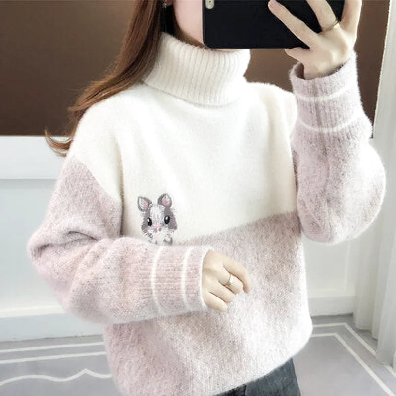 A cozy, two-tone turtleneck sweater in soft white and blush pink with a fluffy texture and an embroidered ham design on the chest