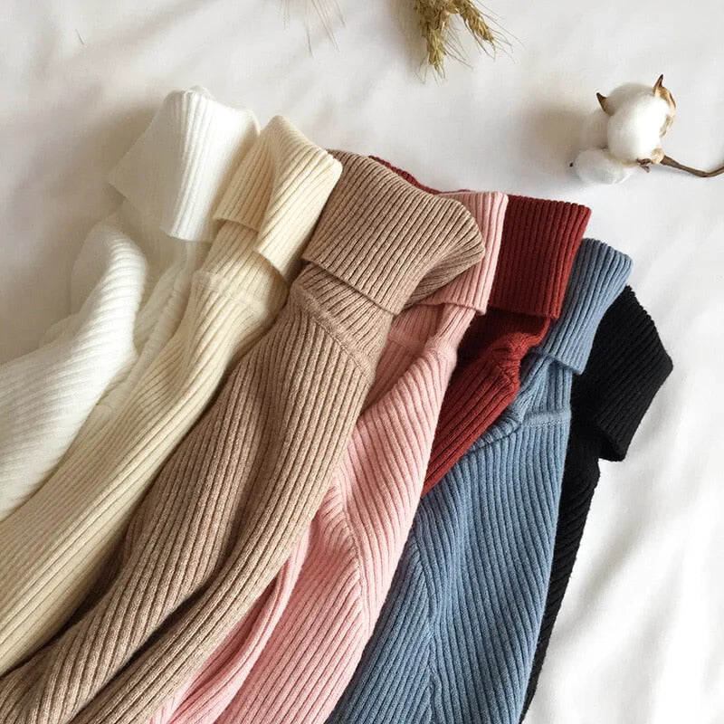 A collection of ribbed knit turtleneck sweaters in soft pastel and neutral tones, including cream, beige, pink, red, blue, and black
