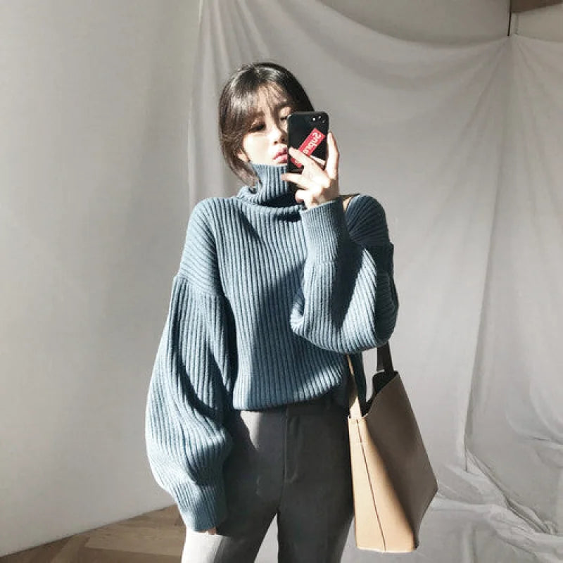 A cozy, ribbed-knit turtleneck sweater in a soft dusty blue hue with voluminous sleeves