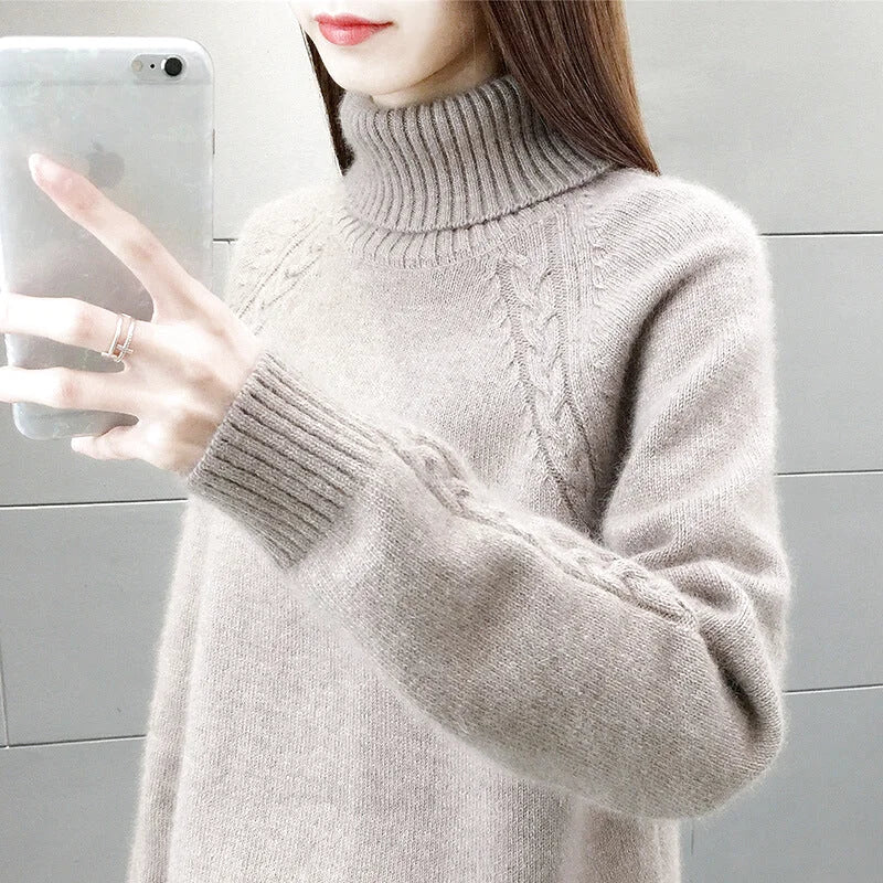 A soft, light gray turtleneck sweater with a ribbed neckline and cuffs, featuring intricate cable-knit patterns along the sleeves