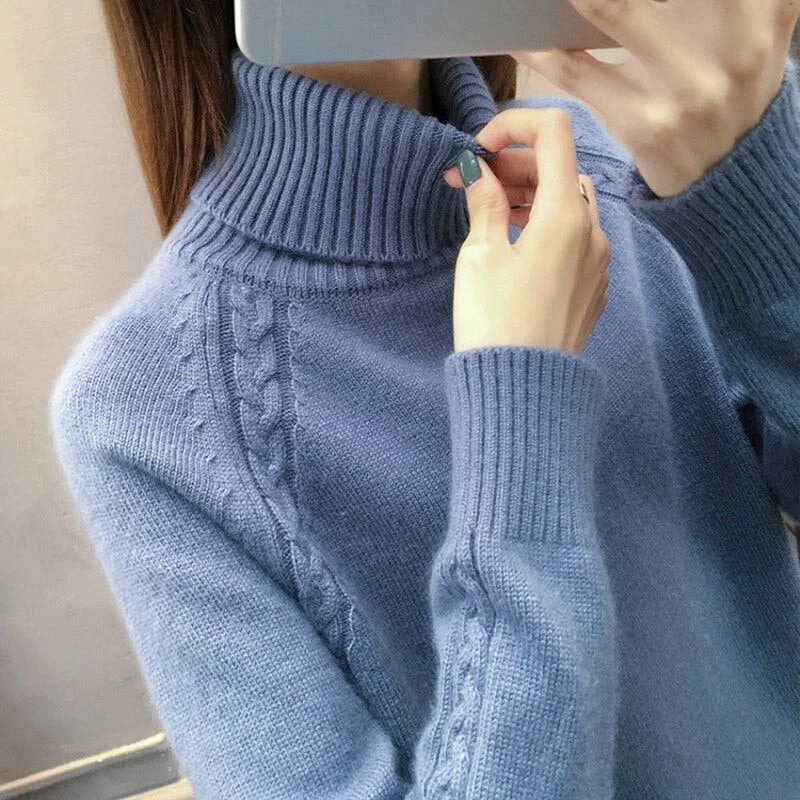 A soft, light blue knit sweater with a ribbed turtleneck and intricate cable-knit detailing along the shoulders