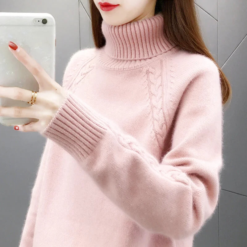 A soft pink, high-necked knit sweater with a ribbed turtleneck and cable-knit detailing on the chest