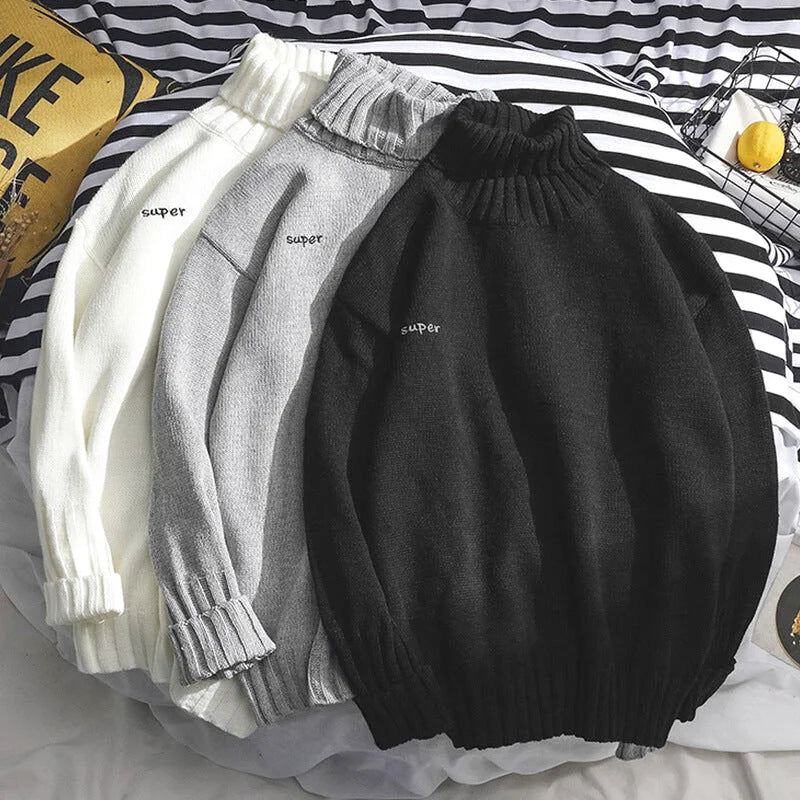 Three cozy, ribbed-turtleneck sweaters in white, gray, and black, each featuring a subtle ’super’ embroidery on the chest
